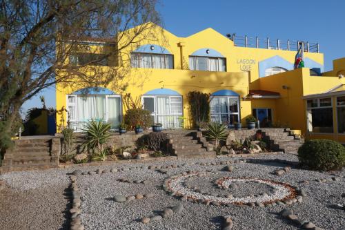 a yellow house with a garden in front of it at Lagoon Lodge in Walvis Bay