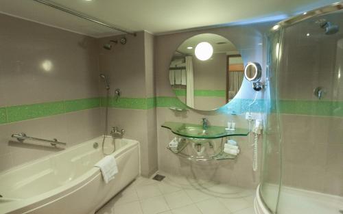 a bathroom with a sink and a tub and a mirror at Lakeshore Hotel & Apartments in Dhaka