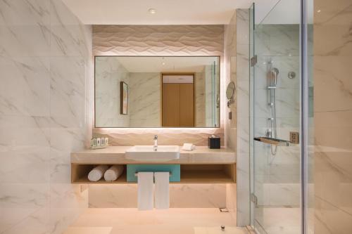 a bathroom with a sink and a mirror at Holiday Inn Tianjin Xiqing by IHG in Tianjin