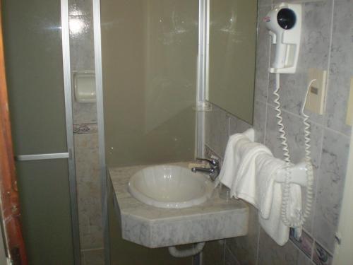 y baño con lavabo, teléfono y toallas. en Hotel Centenario, en Atlántida