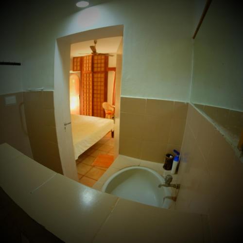 a view of a bathroom with a toilet and a bedroom at New Creation Guest House in Auroville