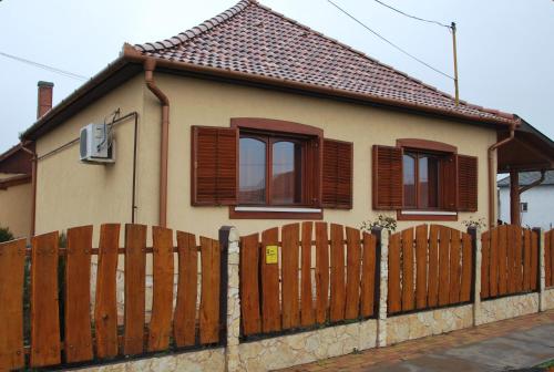 a house with a wooden fence in front of it at Méz-Bor Szállás in Báránd