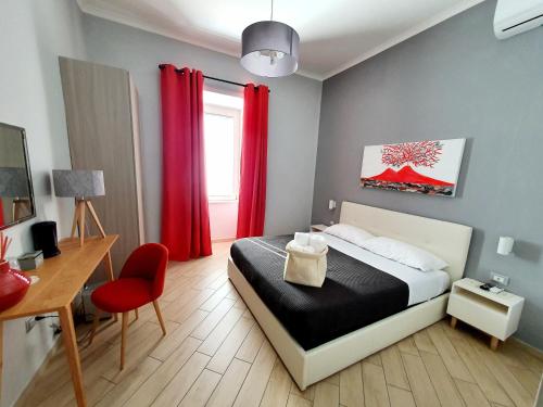 a bedroom with a bed and a desk and red curtains at Solfatara Suites B&B in Pozzuoli