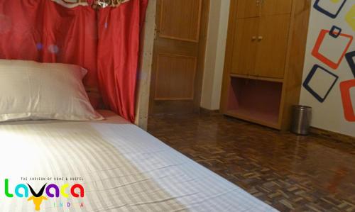 a bedroom with a bed with a red curtain at La Vaca India Manali in Manāli