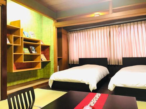 ein Schlafzimmer mit 2 Betten, einem Tisch und einem Regal in der Unterkunft Hotel Takasago in Kōchi