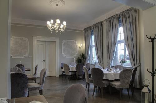 a dining room with tables and chairs and a chandelier at Zespół Pałacowo-Parkowy Bądzów in Polkowice