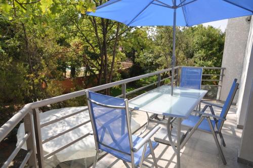 a table and chairs on a balcony with an umbrella at Residence de tourisme Le clos des Vendanges in Moriani Plage