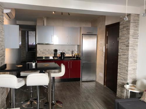 アルダレスにあるApartamento Amapolaのキッチン(赤いキャビネット、白いスツール付)