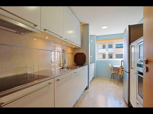 a kitchen with white cabinets and a sink and a table at Comfortable & contemporary - Expo in Lisbon