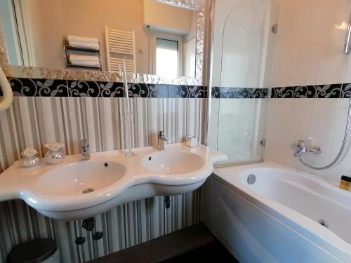 a bathroom with two sinks and a tub and a mirror at Hotel Nordic in Bellaria-Igea Marina