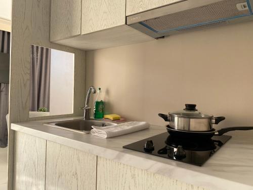 a kitchen with a pot on a stove with a sink at 24K Athena Suites in Athens