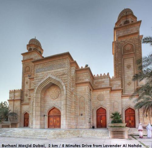 a large stone building with a palm tree in front of it at Lavender Hotel Al Nahda Dubai in Dubai