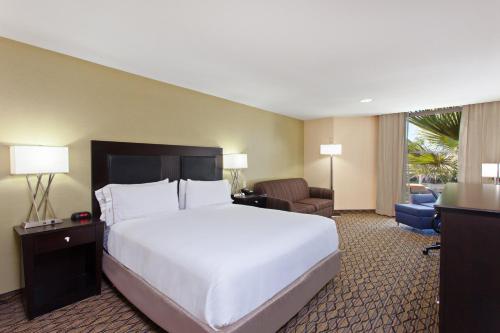 um quarto com uma cama grande e uma sala de estar em Holiday Inn Express Newport Beach, an IHG Hotel em Newport Beach