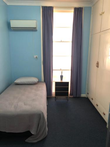a bedroom with a bed and a window at The Pink House in Walgett