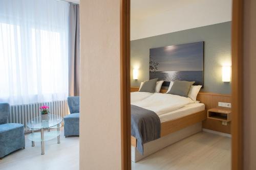 ヴィルヘルムスハーフェンにあるHotel Keilのベッドとテーブルが備わるホテルルームです。