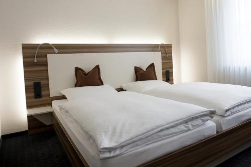 two beds with white sheets and brown pillows at Hotel Kögel in Erbach
