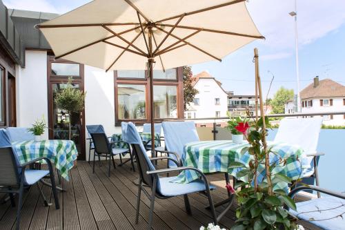 een terras met tafels, stoelen en een parasol bij Hotel Kögel in Erbach