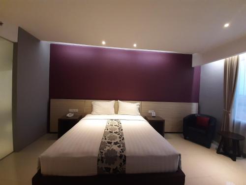 a bedroom with a large bed and a purple wall at Hotel Asri Sumedang in Sumedang