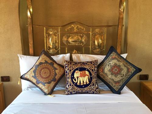 a bed with four pillows on top of it at Djorff Palace in Luxor