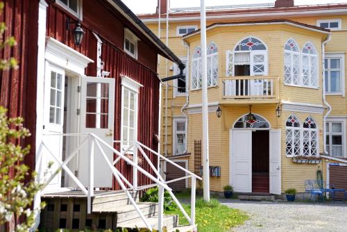 a yellow house with a white door and a red house at Krepelin Apartments in Kristiinankaupunki