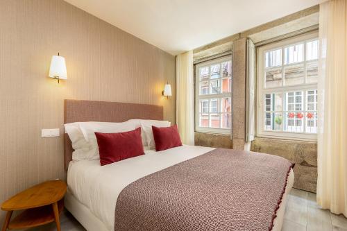 1 dormitorio con 1 cama con almohadas rojas y 2 ventanas en YOUROPO - Ribeira Porto, en Oporto