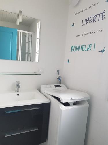 une salle de bain blanche avec un lavabo et un miroir dans l'établissement Appartement T3 au coeur des sables d'Olonne, à Les Sables-dʼOlonne
