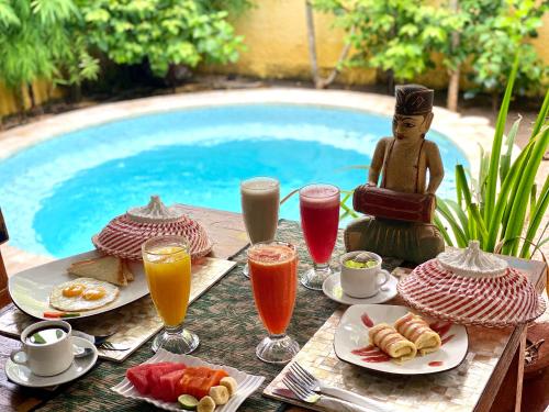 a table with food and drinks next to a pool at Cinta Cottages in Gili Trawangan