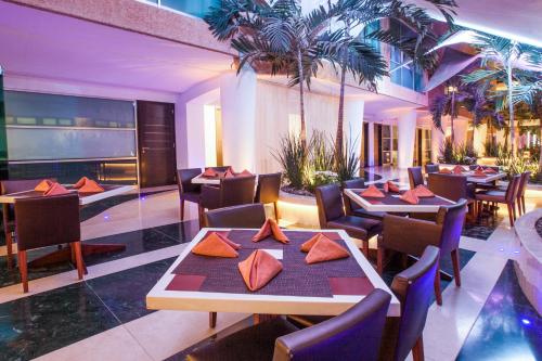 a restaurant with tables and chairs and palm trees at Crowne Plaza Toluca - Lancaster by IHG in Toluca