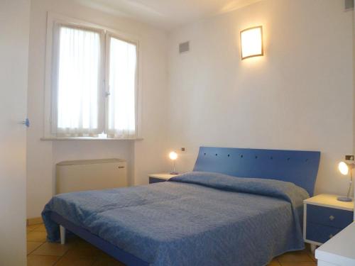 a bedroom with a blue bed and two windows at Residence La Rotonda in Cervia