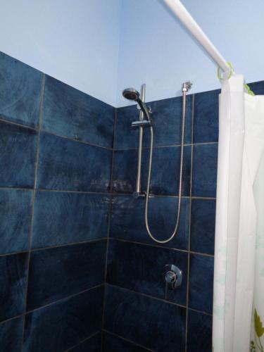 y baño con ducha y pared de azulejos azules. en La Cueva del Che, en Juan Dolio
