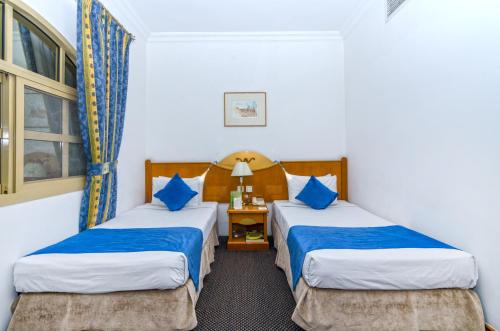 a hotel room with two beds with blue pillows at Zain International Hotel in Dubai