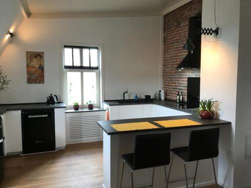 a kitchen with a large island with black counter chairs at Spinnerei in Spechtholzhock
