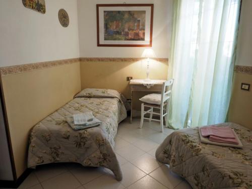a room with two beds and a table and a chair at Casa Margherita Affittacamere B&B in Follonica