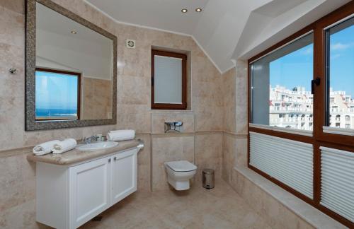 a bathroom with a sink and a toilet and a window at La Mer Penthouse in Varna City