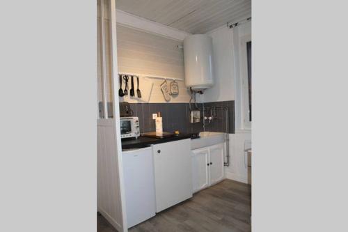 une cuisine avec des armoires blanches et un comptoir noir dans l'établissement Cabourg, Hypercentre, 2 pièces Cosy, à Cabourg