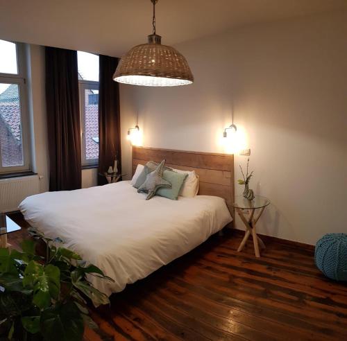 um quarto com uma cama com lençóis brancos e almofadas em Anthos B&B em Maaseik