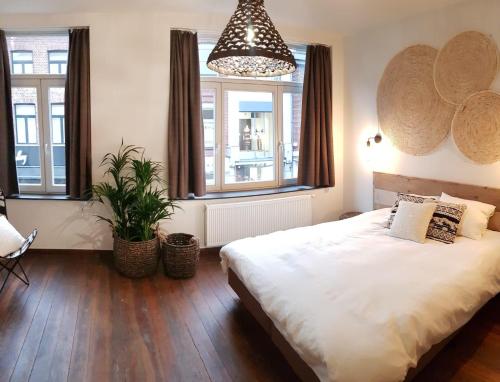 een slaapkamer met een groot bed en een potplant bij Anthos B&B in Maaseik
