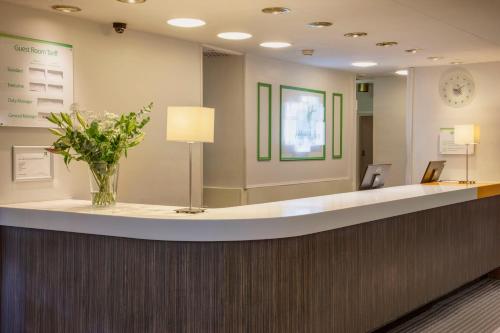 a lobby with a reception counter with a vase of flowers at Holiday Inn Washington by IHG in Washington