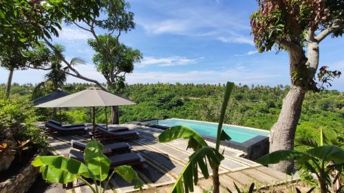 a view of a pool with chairs and an umbrella at Tanah Damai Hotel in Nusa Penida