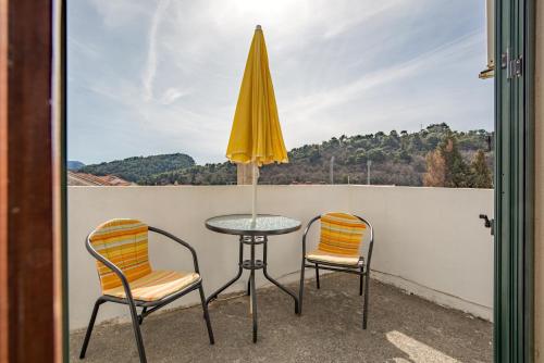 a table and two chairs and an umbrella on a balcony at Guesthouse Drašković in Petrovac na Moru