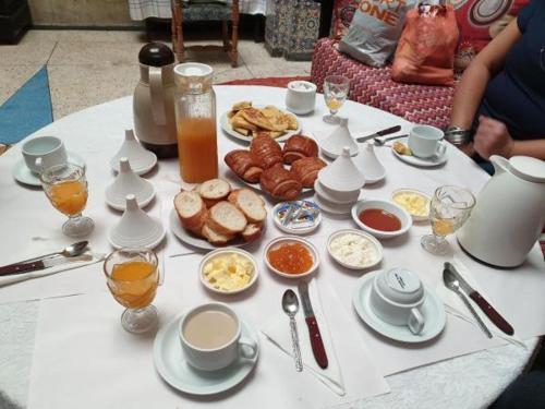 ein weißer Tisch mit Frühstückszutaten und Getränken darauf in der Unterkunft Dar Hlimi in Fès