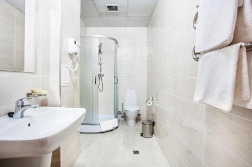 a white bathroom with a sink and a shower at City & Business Hotel in Mineralnie Vody