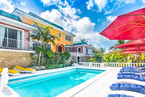 une maison avec une piscine et un parasol rouge dans l'établissement Viking Hill Oceanfront Hostel & Resort, à Nassau