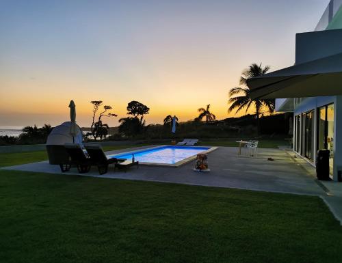 a house with a pool with a sunset in the background at Ocean Breeze Cove - Luxury Retreat in Pedasí Town