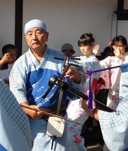 an older man holding a camera in front of a group of people at 民泊コスモス in Yatsuo