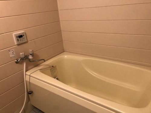 een badkamer met een wit bad en bij ゲストハウスAmaなつ in Amami