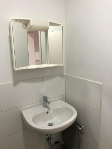 a white bathroom with a sink and a mirror at Apartment in OG Schaupenstiel in Northeim