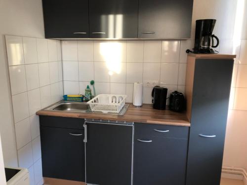 eine kleine Küche mit schwarzen Schränken und einem Waschbecken in der Unterkunft Apartment in OG Schaupenstiel in Northeim