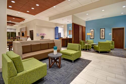 a lobby with green chairs and a couch and tables at Holiday Inn Express & Suites - Galveston Beach by IHG in Galveston