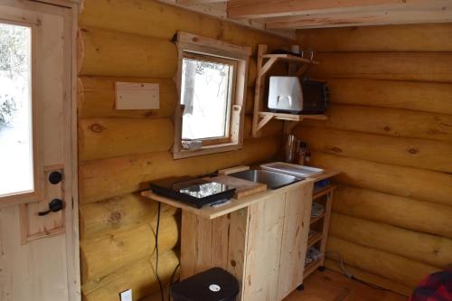 uma cozinha num chalé de madeira com um lavatório e uma janela em Bois Rond Expérience em Saguenay